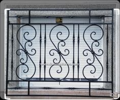 an iron gate with scroll designs on the top and bottom, in front of a brick wall