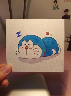 a person holding up a card with an image of a cartoon character sleeping on it