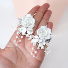 a hand holding two white flowers and pearls