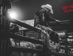 a man in a cowboy hat standing on top of a rail