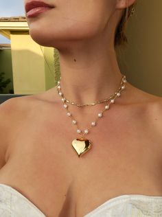 Make a statement with this elegant 18k gold heart pendant! Featuring a pearl chain for added sophistication. Made with 18k plated gold over stainless steel.  Length: 16.5 in with a 2 in extender chain Pendant Width: 30mm Puffy Heart Necklace Outfit, Statement Necklace Aesthetic, Elegant White Chain Necklace For Valentine's Day, Gold Necklace With Pearl Chain For Valentine's Day, Valentine's Day Gold Necklace With Pearl Chain, Valentine's Day Gold Pearl Chain Necklace, Gold Pendant Pearl Necklace With Heart Charm, Gold Heart Necklace With Pearl Charm As Gift, Gold Pearl Necklace With Heart Charm And Pendant