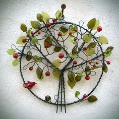 a wire tree sculpture with red berries and green leaves on it's center piece