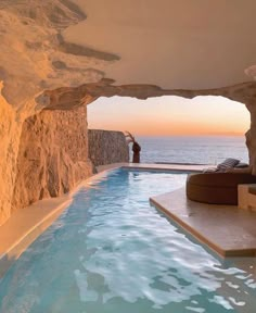 an indoor swimming pool in the middle of a cliff overlooking the ocean at sunset or dawn