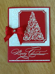 a red and white card with a christmas tree on it's side, tied with a red ribbon