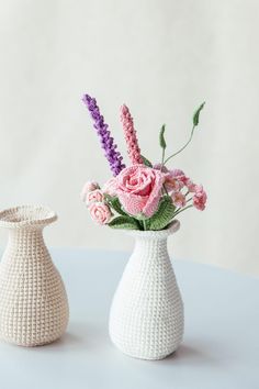 two crocheted vases with flowers in them sitting on a table next to each other