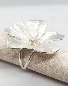 **FREE EXPRESS SHIPPING** This silver ring encapsulates the timeless elegance of nature with a striking buttercup flower as its centerpiece Crafted with meticulous attention to detail, the buttercup is sculpted in exquisite detail, capturing the delicate petals and intricate curves that define this beloved bloom. Set upon a delicate band, the ring is formed by two slender rods that gracefully intertwine and meld into one, symbolizing unity and strength The silver of the band is polished to a rad Flower Silver Ring, Ring Flower, Elegant Handmade Silver Flower Ring, Handmade Flower-shaped Silver Jewelry, Handmade Silver Flower Ring, Adjustable Silver Flower Ring, Adjustable Sterling Silver Flower Ring, Centerpiece Craft, Buttercup Flower