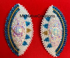 two white and blue beaded brooches on a red background