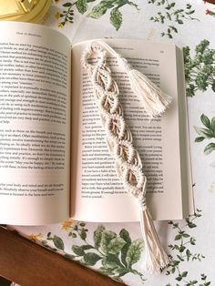 an open book sitting on top of a table next to a candle and some flowers