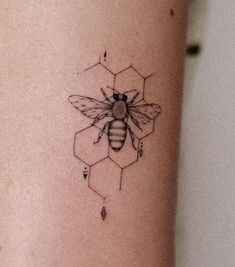 a bee tattoo on the side of a woman's leg with honeycombs