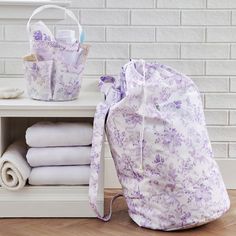 a purple bag sitting on top of a wooden floor next to white towels and blankets