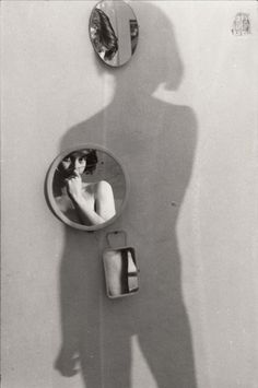 a person standing in front of a mirror with their shadow on the wall next to it