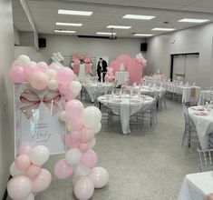 a room filled with tables covered in pink and white balloons