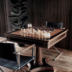 a chess set up on a table with chairs around it and a plant in the background