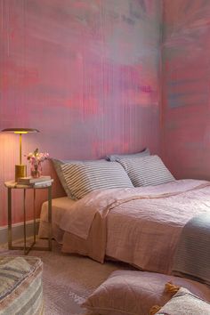 a bedroom with pink paint on the walls and bed in front of it, along with two end tables