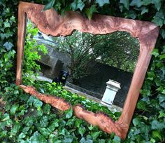 a mirror that is sitting on the ground in front of some bushes and trees,