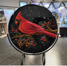 a glass plate with a red bird painted on it's side, sitting on a table