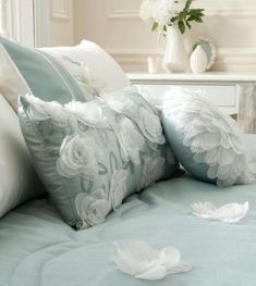 a bed with white flowers on it and blue sheets in front of the headboard