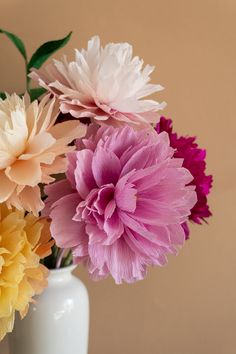 a white vase filled with different colored flowers