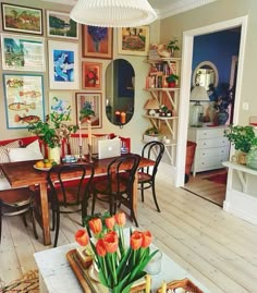 a living room with pictures on the wall and a dining table in front of it