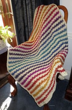 a crocheted blanket sitting on top of a wooden chair