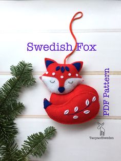 a red fox ornament hanging from a fir tree with the words swedish fox on it