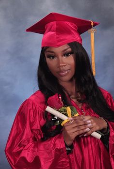 a woman wearing a red graduation gown and holding a diploma