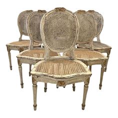 four antique chairs with cane back and wicker seat cushions, all in different sizes