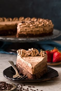 a slice of chocolate cheesecake on a plate with a fork and strawberries in the background