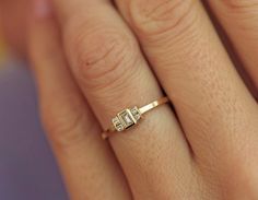 a woman's hand with a diamond ring on her left hand and the other hand holding it