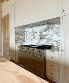 a stove top oven sitting inside of a kitchen next to white cupboards and drawers