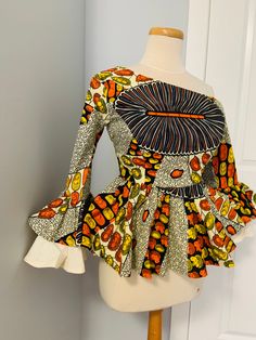 African Print asymmetric peplum top with  double layered sleeves. Made with authentic  100% cotton fabric. Fabric consists for both print and plain.  Neatly sewn, It also comes with a back zipper for easy fit. It can be personalized  with any fabric of your choice. check out our fabric shop https://www.etsy.com/ca/shop/ImpressionsByKhairah?ref=seller-platform-mcnav&section_id=31445897   It's made to order. After placing order, processing time takes 2 weeks because it would be made from scratch t Fitted Long Sleeve Peplum Top For Summer, Fitted Long Sleeve Blouse With Bold Print, Fitted Long Sleeve Peplum Top For Party, Fitted Peplum Blouse With Ruffle Hem, African Print Tops Blouses, Fitted Orange Tops With Ruffles, Fitted Asymmetrical Patchwork Tops, Fitted Multicolor Asymmetrical Top, Peplum Tops For Women