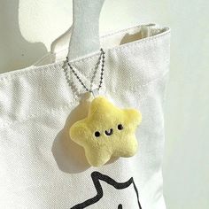 a white bag with a yellow star charm hanging from it's front and side