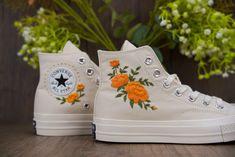 a pair of white shoes with orange flowers painted on them