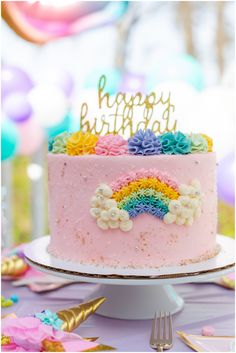 a birthday cake with pink frosting and rainbow decorations