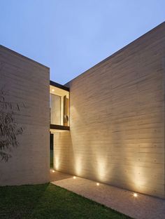 an exterior view of a modern house with lights on the wall and grass in front