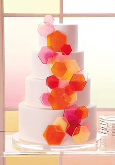 there is a white cake with orange and pink decorations on the bottom tier, sitting in front of a window