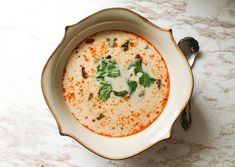 a white bowl filled with soup and garnished with parsley on the side