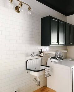 a washer and dryer in a small room with white tile on the walls