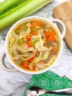 a bowl of chicken noodle soup with celery and carrots on the side