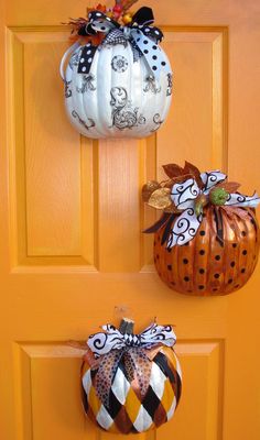 two pumpkins are hanging on the front door, one is decorated with black and white fabric