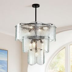 a glass chandelier hanging from the ceiling in a living room with large windows