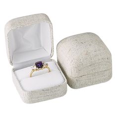 an open ring box with a purple stone in it's center and the lid opened