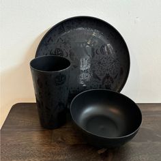 two black cups and saucers on a wooden table