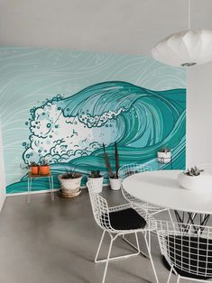 a white table and chairs in front of a blue wave painted on the wall behind it