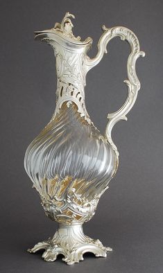 an ornate silver vase sitting on top of a gray tableclothed flooring with white trim around the edges