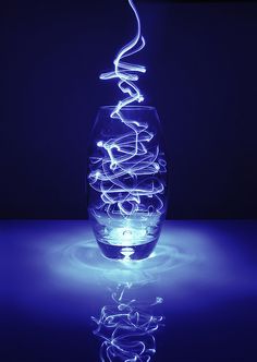 a glass vase sitting on top of a blue table next to a lit candle holder