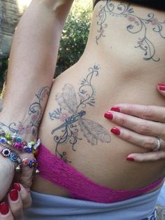 a woman with tattoos on her stomach wearing a pink bra and matching bracelets is holding onto another woman's breast