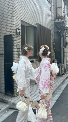 two women in kimonos walking down the street with bags on their back legs