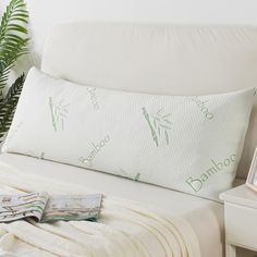 a bed with a white comforter and green bamboo pillow on it's side