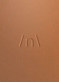 the letter m is inscribed in sand on a brown surface with two small white letters